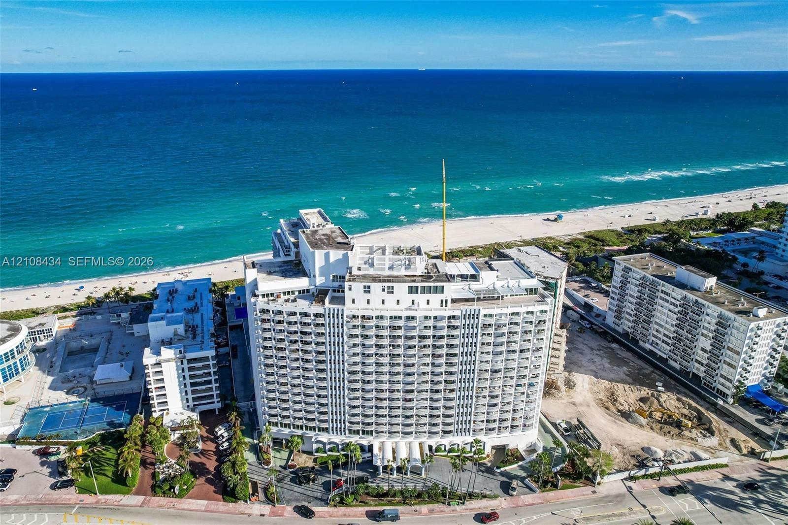 High-rise multi-story building featuring tiered balconies, a rooftop deck, and direct proximity to the oceanfront
