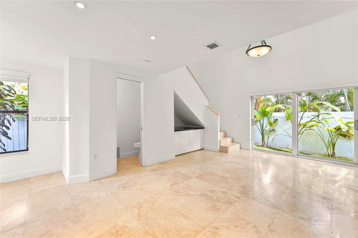 Interior space featuring large-format tile flooring, sliding glass doors, recessed lighting, and built-in cabinetry beneath an integrated staircase