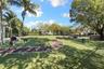 Expansive outdoor recreation space featuring a manicured lawn, curved walking path, mature shade trees, and perimeter landscaping