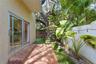 Exterior patio featuring red brick paving, sliding glass doors, synthetic turf landscaping, and a concrete masonry wall