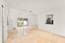 Open-concept living space featuring high ceilings, light-toned stone-finish flooring, recessed lighting, and large sliding glass doors