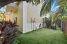 Stucco exterior, fenced yard with synthetic turf, mature landscaping, and sliding glass door entry