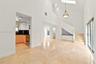 Open-concept living space featuring high vaulted ceilings, large skylight, natural stone flooring, custom built-in cabinetry, and sliding glass doors