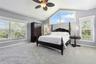 Vaulted ceiling featuring a ceiling fan, neutral carpeting, and oversized windows including a geometric transom window