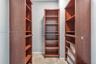 Built-in floor-to-ceiling wood-finish shelving units with adjustable shelving and integrated slide-out storage drawers