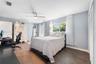 Bedroom featuring dark wood-finish flooring, a contemporary brushed-nickel ceiling fan, multi-pane windows, and white louvered closet doors