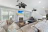 Living area featuring dark wood-finish flooring, recessed lighting, ceiling fans, and a fireplace with a textured stone surround and mantle