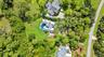 Aerial perspective of residential property featuring a metal roof, private swimming pool, concrete driveway, stone walkway, and expansive mature lands
