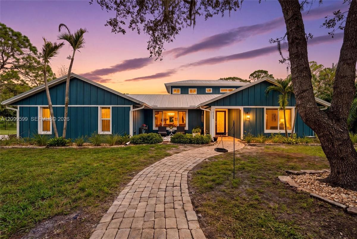 Board-and-batten siding exterior, metal roof, stone-paver walkway, and mature landscaping