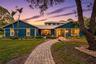 Board-and-batten siding exterior, metal roof, stone-paver walkway, and mature landscaping