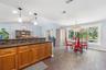 Kitchen featuring wood cabinetry, stone-finish countertops with a mosaic tile backsplash, wood-finish flooring, vaulted ceilings, and large windows wi