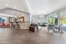 Open-concept interior featuring wood-finish tile flooring, vaulted ceilings, built-in shelving, glass sliding doors, and a decorative breakfast bar