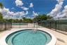 In-ground circular spa featuring a concrete surround, metal perimeter fencing, and a nearby lap pool