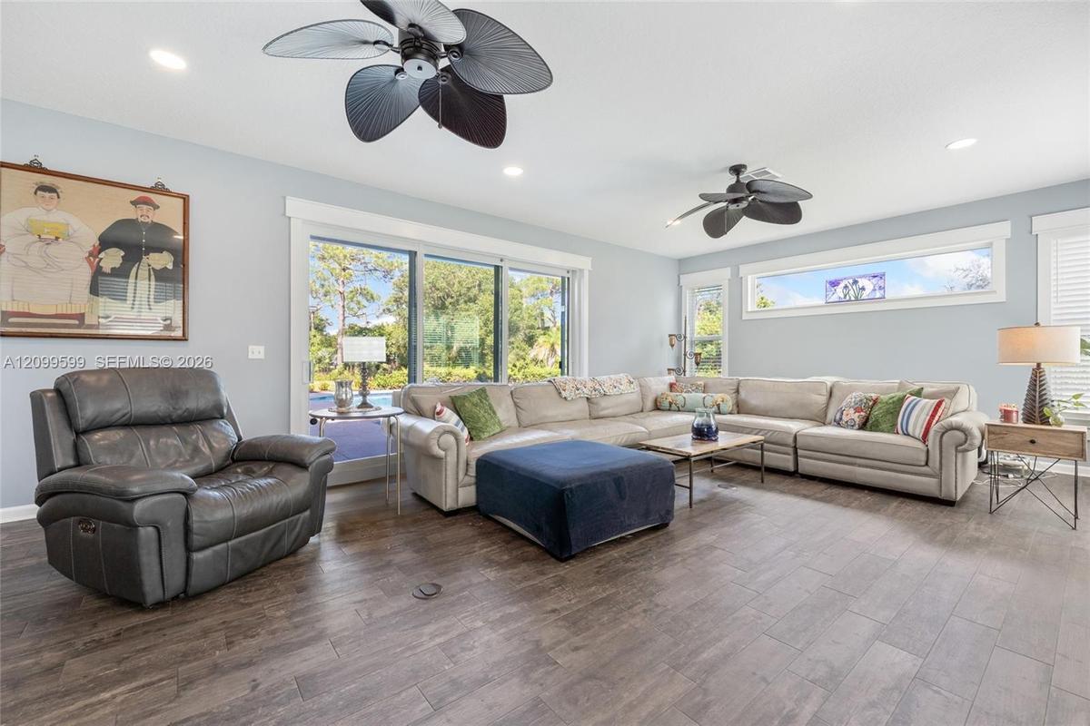 Living area featuring wood-finish flooring, two multi-blade ceiling fans, recessed lighting, and expansive sliding glass doors