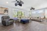 Living area featuring wood-finish flooring, two multi-blade ceiling fans, recessed lighting, and expansive sliding glass doors
