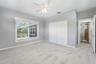 Neutral wall color, carpeted flooring, large window with blinds, bi-fold closet doors, and a ceiling fan with integrated lighting