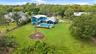 Aerial perspective of a multi-level residence featuring a metal roof, an in-ground swimming pool with a stone paver deck, a circular stone fire pit, a