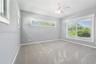 Neutral-toned walls with high-set horizontal windows, a large multi-pane window, wall-to-wall carpeting, and a ceiling-mounted fan with integrated lig