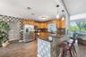 Kitchen featuring wood cabinetry, stainless steel appliances, stacked stone backsplash, and a breakfast bar with stone-finish countertop and pendant l