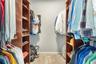 Walk-in closet featuring floor-to-ceiling wooden built-in shelving, integrated hanging rods, and neutral carpeting