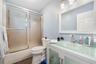 Bathroom featuring a vanity with an integrated glass sink and countertop, frosted glass cabinet inserts, a shower enclosure with decorative etched gla