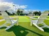 Synthetic turf recreational area featuring a multi-sport court with perimeter fencing and tall exterior lighting