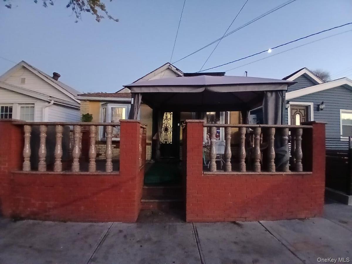 Front patio featuring red masonry walls, stone-finish balustrades, and a decorative metal entry door