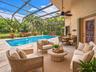 Screen-enclosed patio featuring a concrete deck, newly resurfaced swimming pool, and ceiling fan - virtually staged