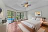 Master bedroom, tray ceiling, wood-finish flooring, and large sliding glass doors providing outdoor access-virtually staged