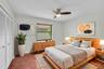 Bedroom featuring wood-finish flooring, white louvered closet doors, a central ceiling fan with integrated lighting, and a window with a neutral rolle