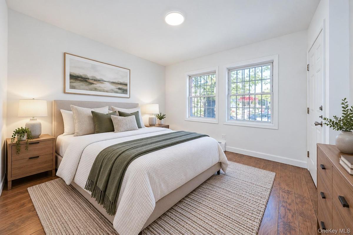 Neutral-toned interior featuring wood-finish flooring, dual windows with grid detailing, and recessed ceiling lighting