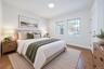 Neutral-toned interior featuring wood-finish flooring, dual windows with grid detailing, and recessed ceiling lighting