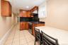 Kitchen featuring wood cabinetry, stone countertops, stainless steel gas range, stainless steel range hood, and tile flooring