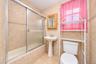 Full-wall tile surround with decorative accent border, sliding glass shower door, porcelain pedestal sink, and wooden medicine cabinet