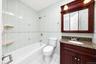 Bathroom featuring a vanity with stone-finish countertop, decorative tile surround, built-in medicine cabinet with integrated lighting, and a bathtub 