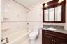 Bathroom featuring a wood-tone vanity with a stone-finish countertop, integrated oval sink, built-in medicine cabinet, and tub-shower combination with