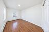 Interior room featuring wood-finish flooring, white walls, dual-pane windows, and a sliding-door closet