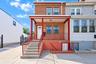 Brick facade exterior featuring a covered front porch, concrete steps, metal railings, and dual-pane windows with security bars