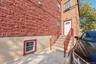 Exterior featuring red textured masonry, tan stucco lower siding, concrete staircase with metal railings, and white entry door with arched transom win
