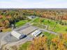 Extensive acreage featuring a large outdoor riding arena, a private pond, multiple outbuildings, and fenced pastures