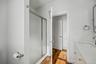 Shower enclosure with a metal frame, vanity featuring a stone countertop with an integrated sink, metal wall-mounted hardware, and wood-finish floorin