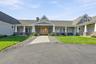 Exterior featuring a horizontal siding facade, stone masonry accents, a covered front porch with white columns, a paved walkway, and double wood-finis