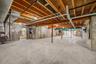 Unfinished lower level featuring exposed wood joist ceilings, poured concrete foundation walls, and concrete flooring. High ceilings!