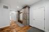 Custom-built cabinetry with wood-finish doors, integrated bench seating, horizontal shiplap wall paneling, and wide-plank wood-finish flooring