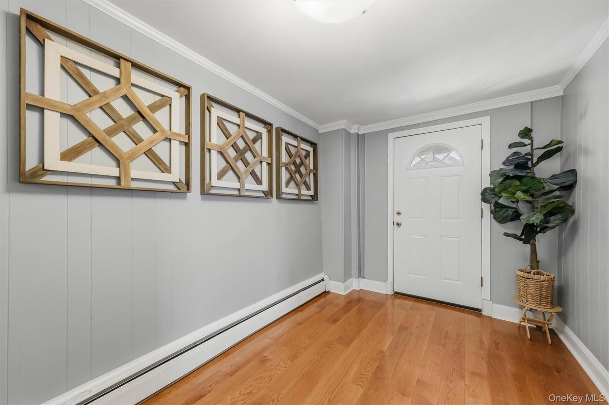 Bright and welcoming interior foyer featuring gleaming hardwood floors and crisp neutral tones.