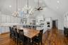 Vaulted ceilings, wood-finish flooring, custom shaker-style cabinetry, stone countertops, and tiered chandelier lighting