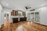 Wet bar featuring dark cabinetry, live-edge wood countertop, stainless steel dishwasher, glass-front upper cabinets, and wood-finish flooring