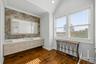 Dual-sink vanity with rectangular vessel basins, quartz countertop, textured mosaic tile backsplash, wood-finish flooring, and vaulted ceiling