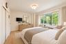 Wood-finish flooring, large multi-pane windows, and a flush-mount modern ceiling fixture