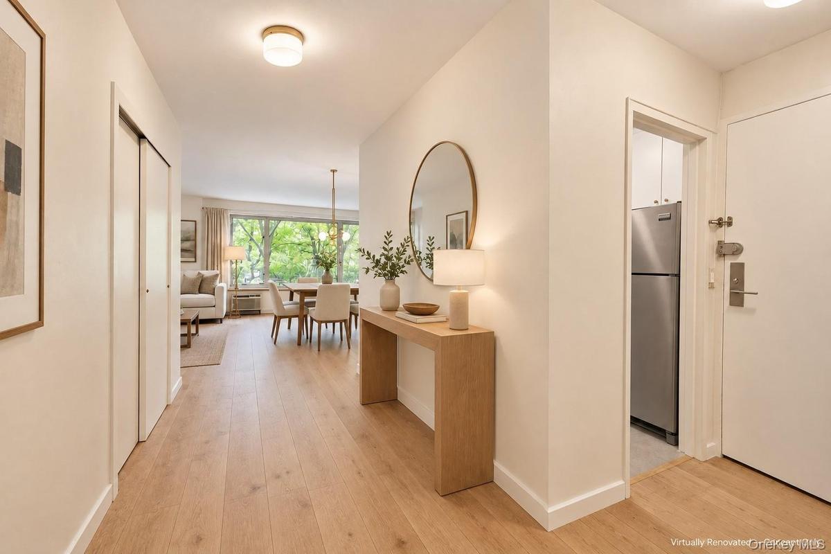 Entryway featuring wood-finish flooring, white flush-panel closet doors, and a ceiling-mounted globe light fixture